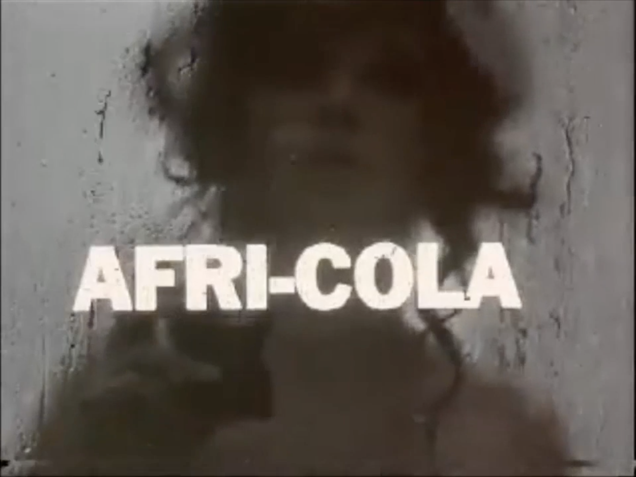 "AFRI-COLA" in all caps in front of a water-streaked window, behind which is the silhouette of a woman.